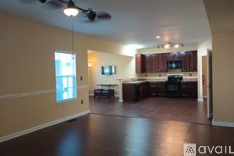 A spacious living room with a kitchen in the background.