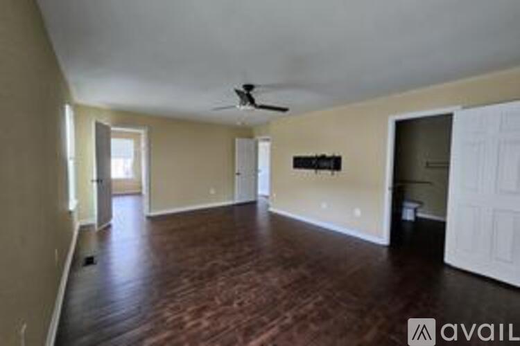 A spacious room with wood flooring and a ceiling fan.