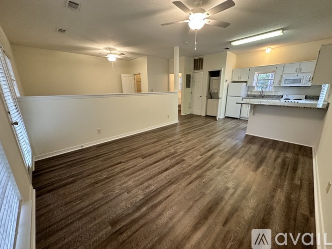 A spacious room with wooden flooring and a ceiling fan.