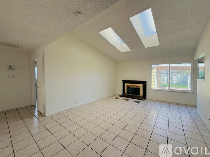 A spacious room with a fireplace and skylights.