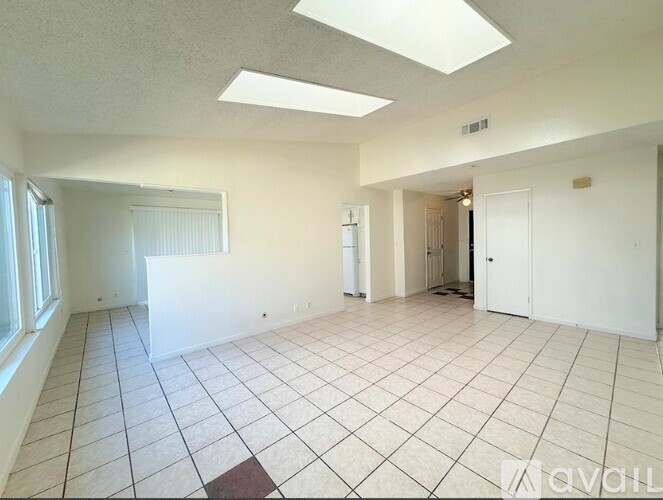 A spacious room with white walls and a tiled floor.