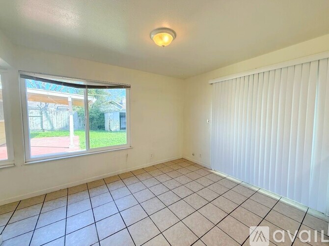 A room with a tiled floor and a window with blinds.