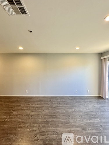 A room with a wooden floor and a wall with a light switch.