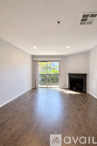 A large empty room with a fireplace and wooden floors.