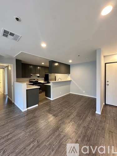 A modern kitchen with dark wood floors and white walls.