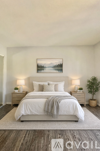 A bedroom with a large bed, two nightstands, and a painting on the wall.