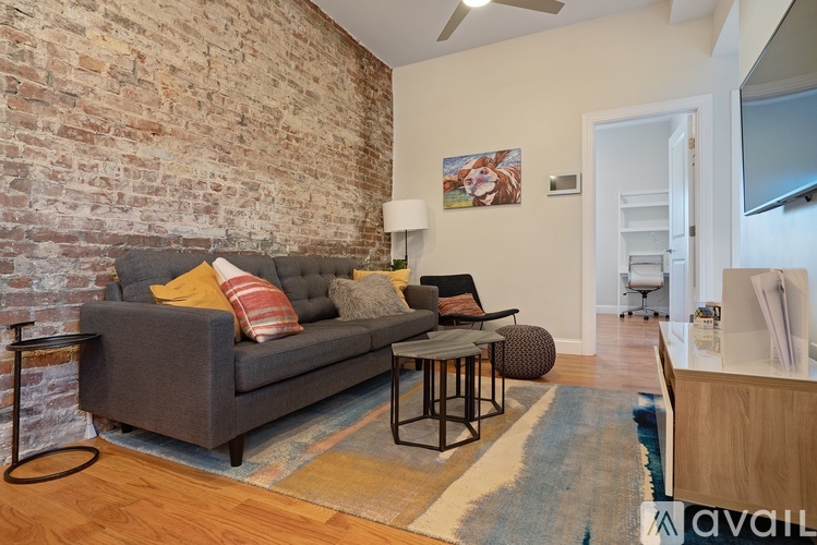 A living room with a grey couch and a brick wall.