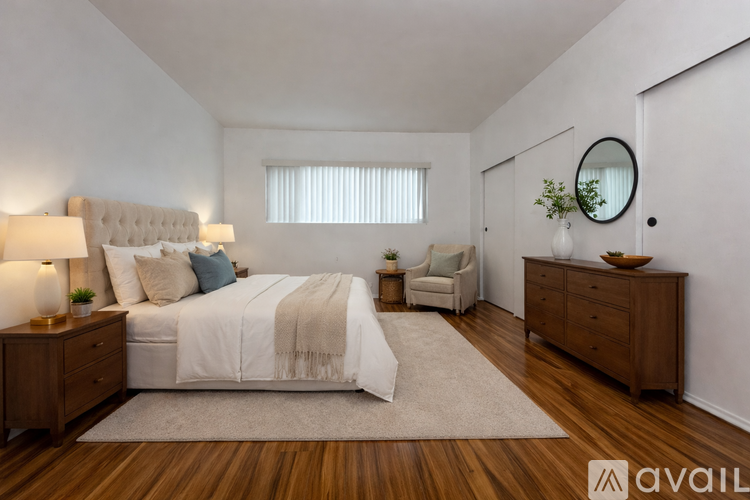 A bedroom with a large bed, a chair, and a dresser.