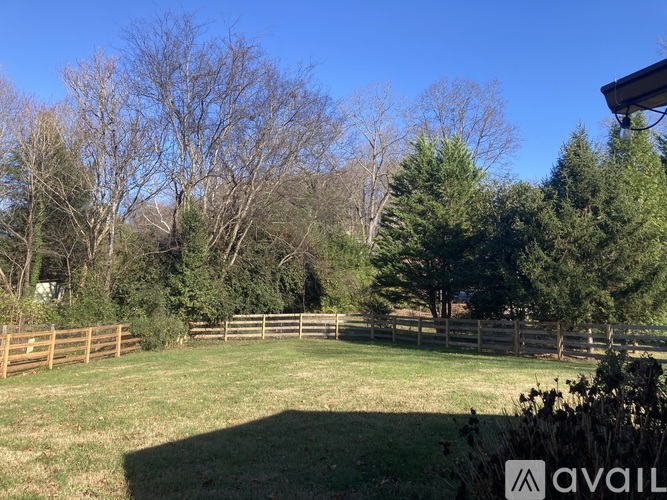 A grassy field with trees and a wooden fence.