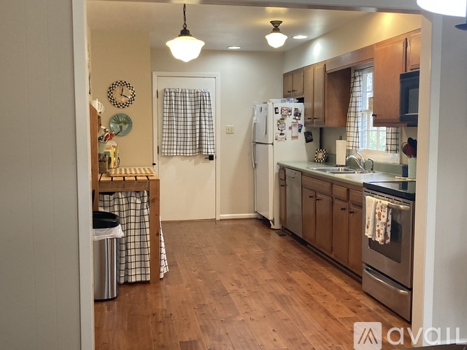 A kitchen with wooden floors and a refrigerator in the middle.
