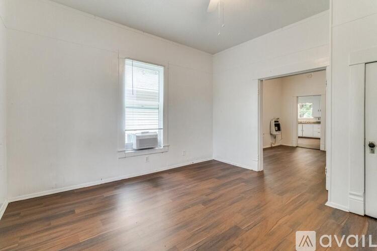 A room with wooden floors and white walls is available for rent.