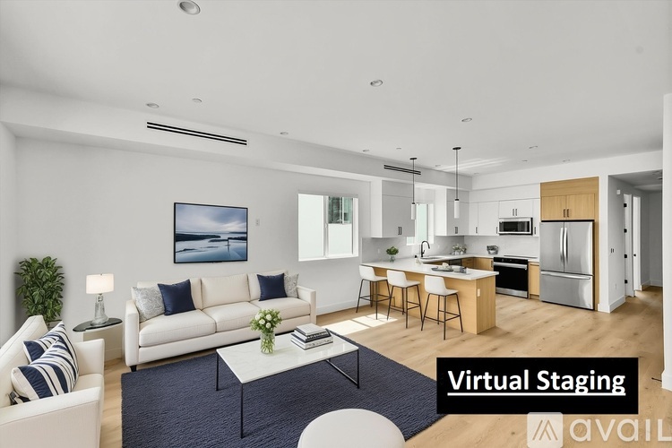 A modern living room with a couch, coffee table, and kitchen area in the background.