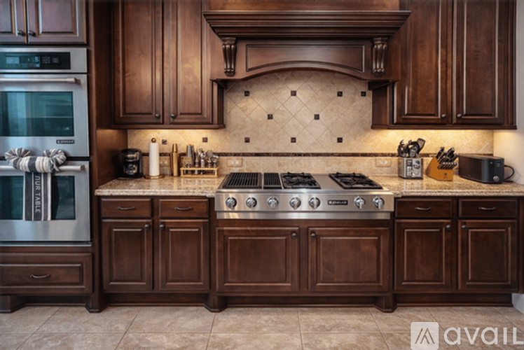 A kitchen with dark wood cabinets and a granite countertop.