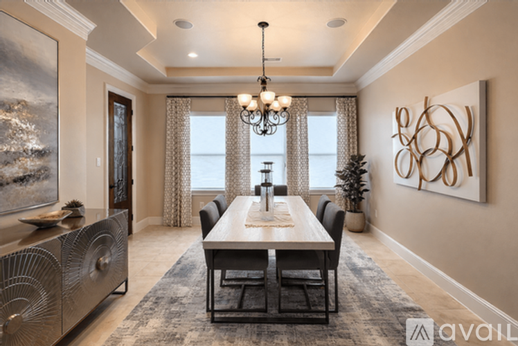 A dining room with a wooden table and chairs, a chandelier, and a large painting on the wall.