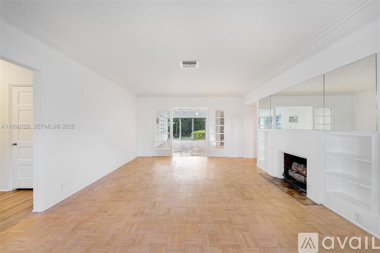 A spacious room with wooden flooring and a fireplace.