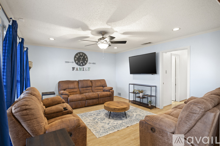 A living room with brown furniture and a flat screen TV mounted on the wall.
