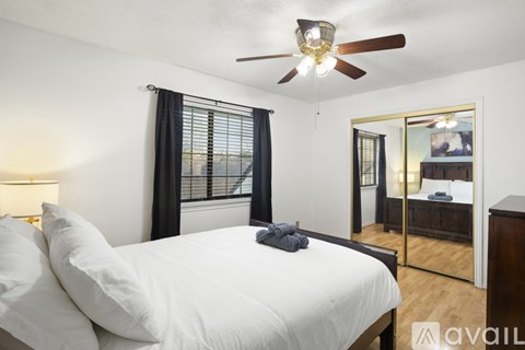 A bedroom with a large bed and a ceiling fan.