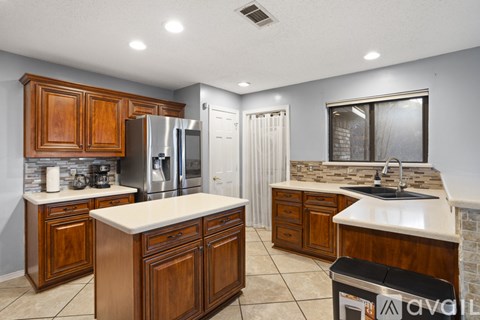 A kitchen with wooden cabinets and a stainless steel refrigerator.