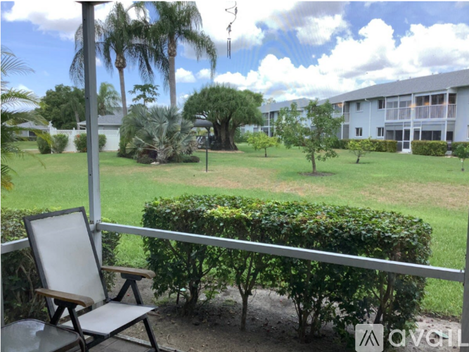 A chair is on a balcony overlooking a green lawn.