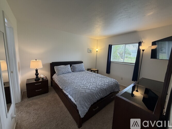 A bedroom with a bed, nightstand, and lamp.