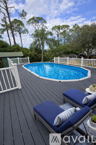 A pool surrounded by a deck with two lounge chairs.