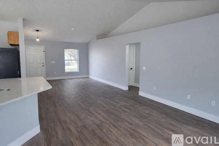 A spacious living room with wood flooring and white walls.