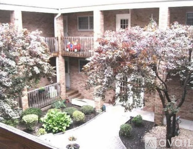A balcony with a table and chairs is surrounded by flowering trees.