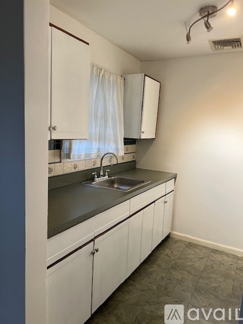 A kitchen with white cabinets and a stainless steel sink.