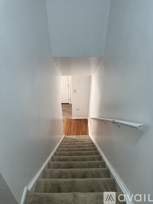 A staircase with a carpeted runner and a wooden door at the top.