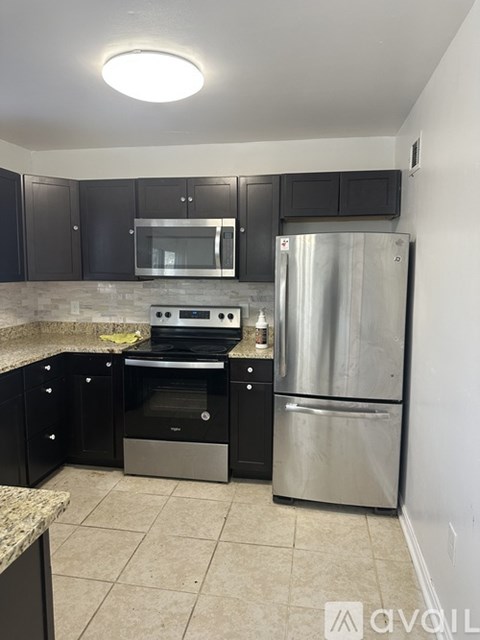 A kitchen with black cabinets and stainless steel appliances.