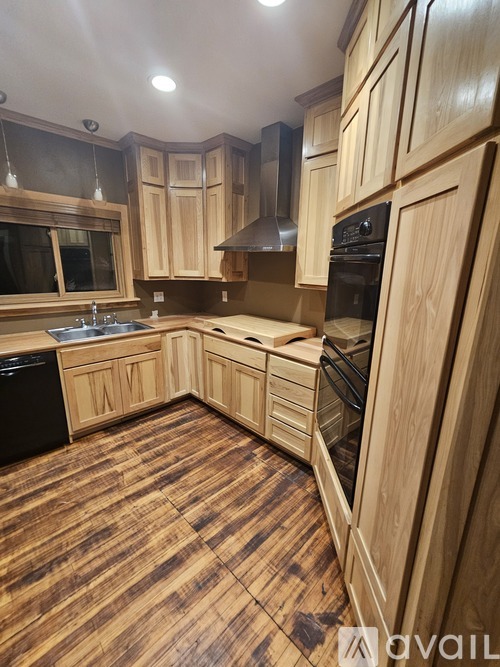 A kitchen with wooden cabinets and a black dishwasher.