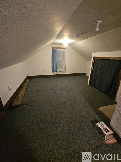 A room with a carpeted floor and a window with curtains.