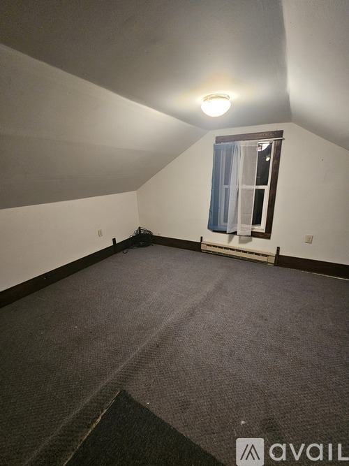 A room with a carpeted floor and a window with curtains.