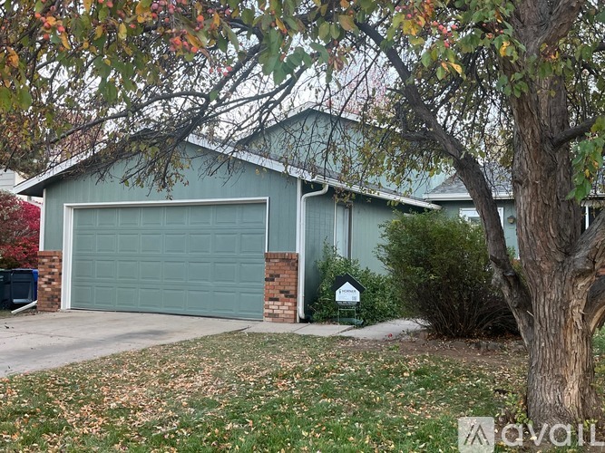 A house with a green garage door and a tree in front.