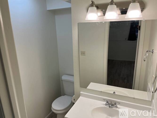 A white bathroom with a toilet, sink, and mirror.