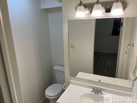 A white bathroom with a toilet, sink, and mirror.