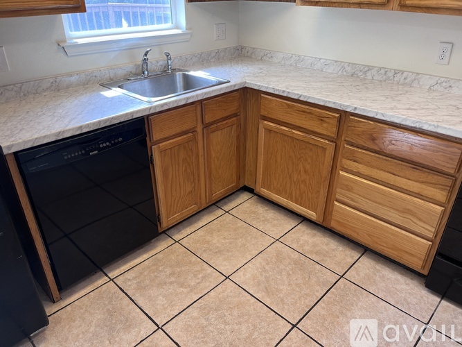 A kitchen with wooden cabinets and a black dishwasher.