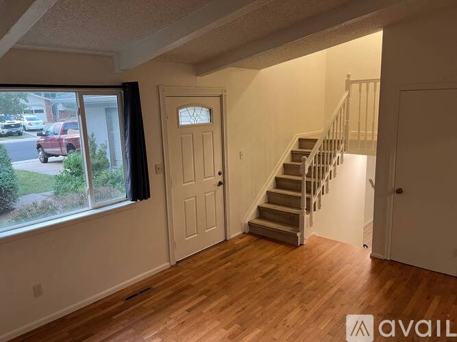 A room with wooden floors and a staircase leading to another room.