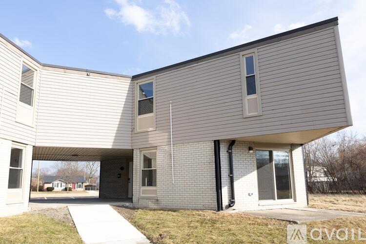 A modern house with a grey exterior and a white walkway leading to the entrance.