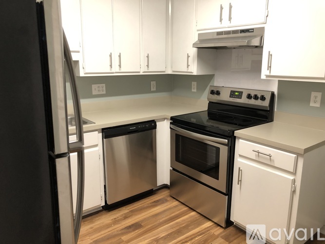 A kitchen with a black fridge, stainless steel dishwasher, and oven.