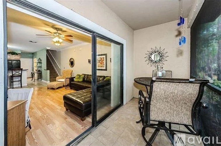 A living room with a black couch and a glass door leading to a balcony.