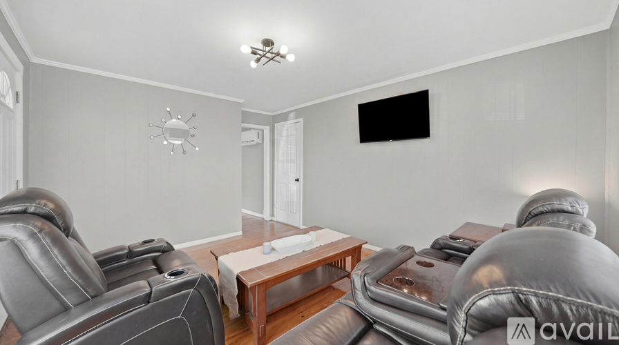 A living room with grey leather sofas and a wooden coffee table.