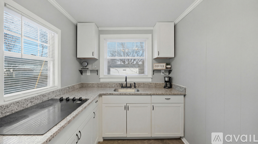 A kitchen with white cabinets and a marble countertop.