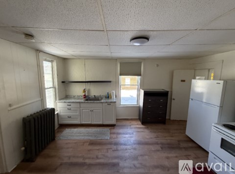 A kitchen with white cabinets and a refrigerator.