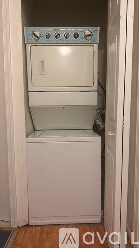 A white dishwasher with a blue control panel is in a small space.