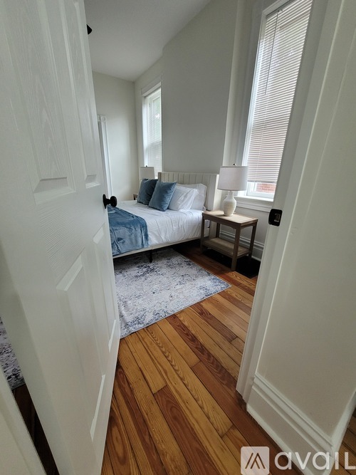 A bedroom with a bed, nightstand, and window.