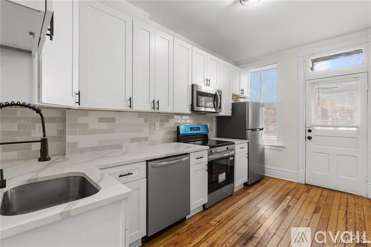 A kitchen with white cabinets and wooden floors.