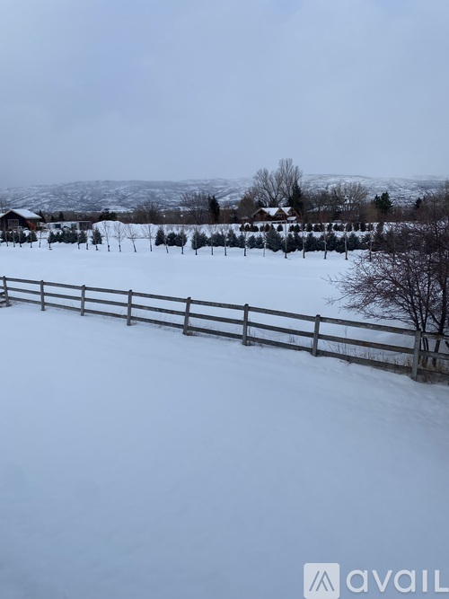 A snowy landscape with a wooden fence in the foreground.
