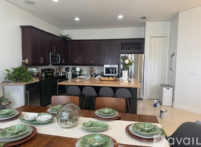 A modern kitchen with dark brown cabinets and a dining table set with green plates.