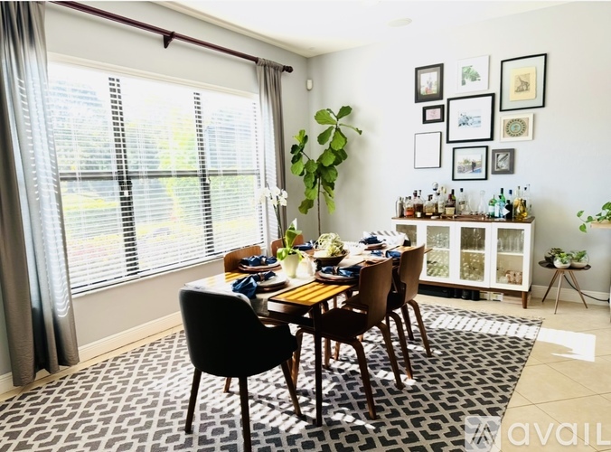 A dining room with a table set for four and a potted plant on the table.